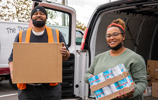 smiling community organizers holding food donations