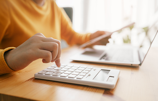 close-up of hand calculating costs on calculator