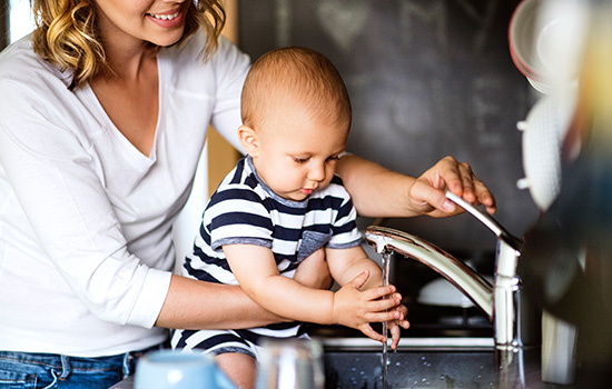 young mother with a baby doing housework in kitchen