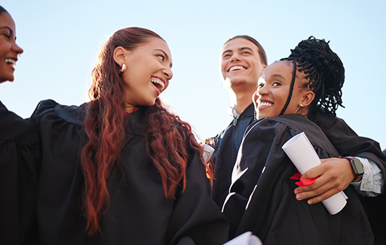 group of smiling high school graduates at outdoor ceremony