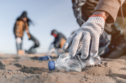 hand picking up an empty plastic bottle on beach